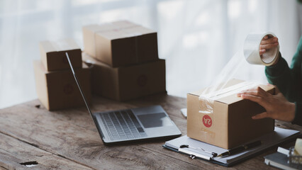 People packing products into parcels, online store owners checking orders before shipping to...