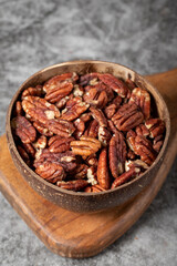 Pecan on dark background. Pecans in a coconut bowl. healthy fat. Heap shelled Pecans nut. Close up. Keto diet. Studio shoot. close up