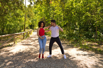 Handsome young man and woman dancing bachata and salsa in the park. The couple dance passionately...