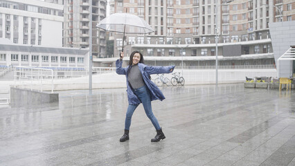 Young asian woman dancing with umbrella in rain, enjoying weather, good mood