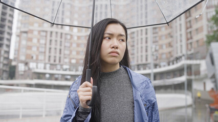 Brunette woman walking on street under rain with umbrella, bad mood, break-up