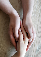 woman and child hands with a white heart on a wooden background