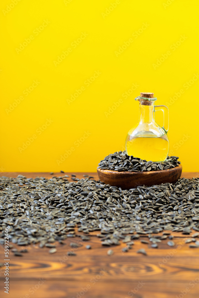 Wall mural oil and sunflower seeds on  wooden table on  yellow background - Wall murals