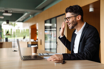 Young businessman in formal wear using laptop while working at office