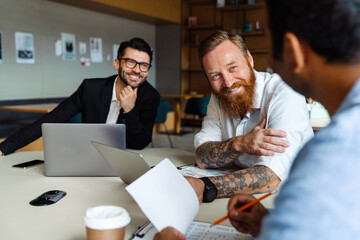 Multinational businessmen using laptops and documents working at office