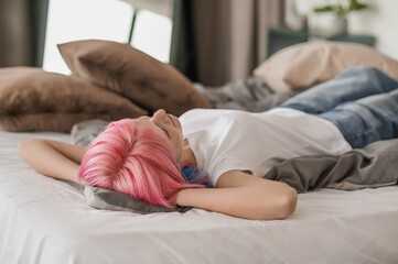 Thoughtful pink-haired girl resting in the bedroom