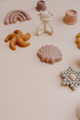 Stylish cute pastel colourful baby kid children educational toys on light pastel pink background. Aesthetic hygge baby toys collage with blank copy space. Teether, sand molds, stacking cups