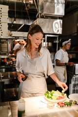 Young white chef woman cooking while working in restaurant kitchen
