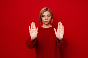 Young blonde woman with short hair doing stop gesture with hands