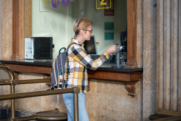 Adult 35s year old lesbian woman in plain shirt and jeans with backpack and sunglasses traveling by...