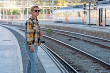 Adult 35s year old lesbian woman in plain shirt and jeans with backpack and sunglasses traveling by train in Europe. Train station in Barcelona, Spain.