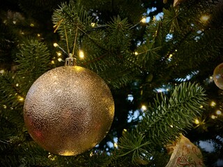 Shiny ball on a Christmas tree with garlands, close-up. Concept: winter weekend and new year holidays. Christmas tree decoration on Christmas Eve.