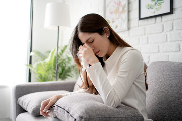 Unhappy Asian woman sitting on sofa at home She was crying with a handkerchief. She is sad after an...