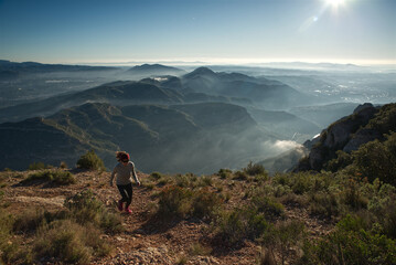Fototapeta na wymiar Woman runs through the mountains of Montserrat in Catalonia, Spain.