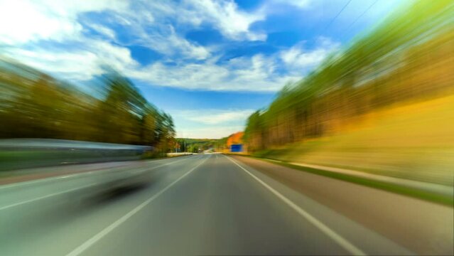 Bright Motion Timelapse of a Speedy Day Drive Near a Big City, Streets and Trees All Turning Into Abstract Blur. Hyperlapse Road Trip Travel Concept Sort of Dashcam POV. Windshield View
