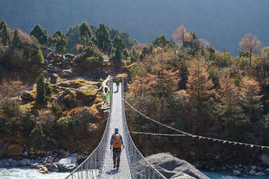 Hiker crossing a suspension bridge on the Kanchenjunga trek near Ghunsa, Nepal