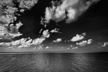Dramatic sea view, monochrome  seascape, white clouds dark deep ocean bay. Coastline in black and...