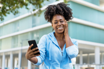 African american woman with phone receiving message from boyfriend
