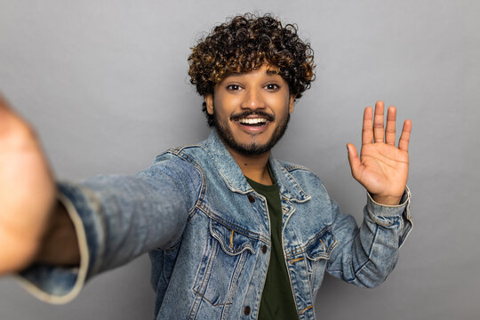 Young Indian man doing selfie shot pov on mobile phone on grey background