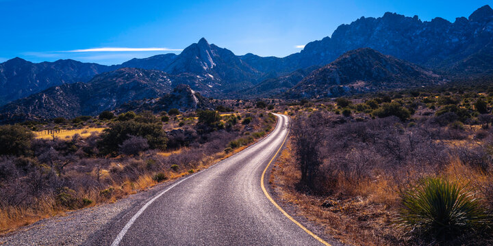 Organ Mountains, Desert Peaks National Monument in Las Cruces, Doña Ana County, New Mexico, Southwestern USA, curved single lane paved road to Sugarloaf Peak through arid desert valley meadow at dusk.
