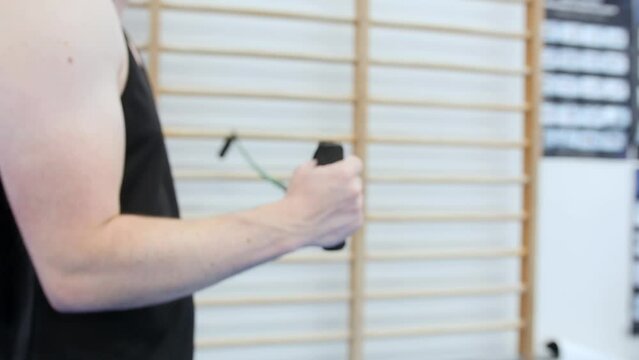 Male athlete performing shoulder rehabilitation exercise with elastic band