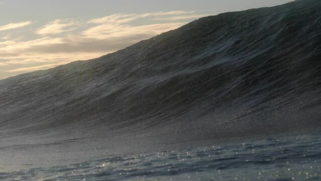 A heavy short wave breaks over a shallow rock ledge as the sun rises in the background on the east coast of Australia