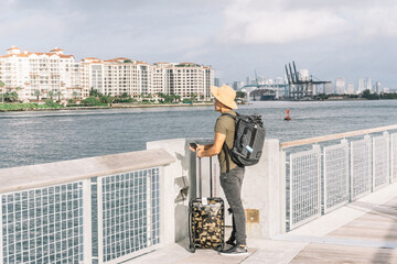 Young man with a suitcase and a backpack, arriving on the shores of Miami,