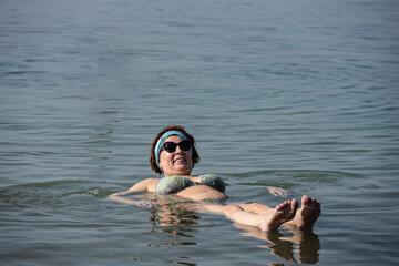 woman in glasses bathes in the waters of the Dead Sea