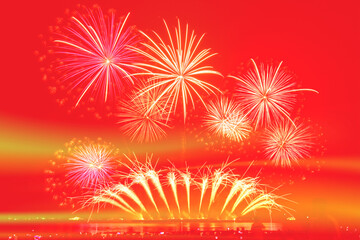 Gold fireworks celebration on red background.