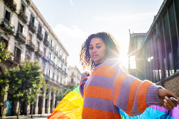 Ethnic woman on street with rainbow flag