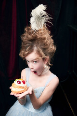 Portrait of cute little girl, child in image of medieval royal person emotionally looking on cake. Birthday. Concept of historical remake, comparison of eras