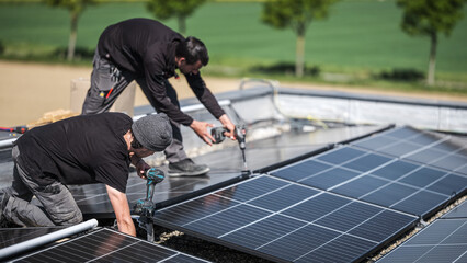 Male team engineers installing stand-alone solar photovoltaic panel system. Electricians mounting...