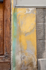 old yellow, green, grey wall background with staines, wooden door, stone wall; close up