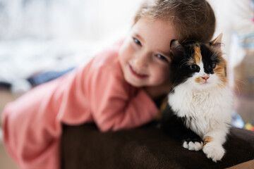 Baby girl with kitty lying on the sofa. Children's love for pets.