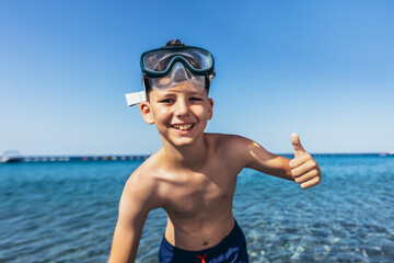 Portrait of a smiling little boy with scuba mask by the sea