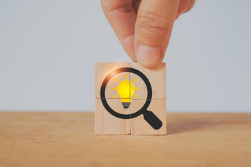 hand completed square wood cube block with magnifying glass and brighten lightbulb icon for idea,...