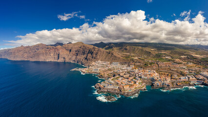 Aerial view of the city of Los Gigantes and the surrounding majestic cliffs. Sunny weather highlights the colors of the water.