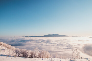 Fabulous winter scenery with a view of the sea of clouds illuminated by the sun in the morning. Sunrise glistens on the newly snow-covered ground. Beskydy mountains, Czech Republic