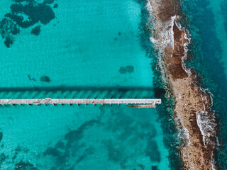 Drone photo of the ocean with reef and jetty