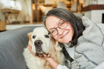 Elderly woman cuddling her dog on the sofa