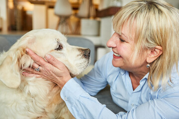 Happy senior woman stroking her retriever dog