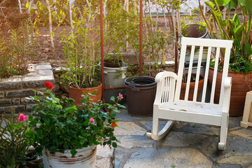 White chair next to potted plants, cute patio with rocking chair, courtyard with flowers