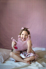 Happy kid girl with soft crown shaped pillow. Princess girl. Pink.