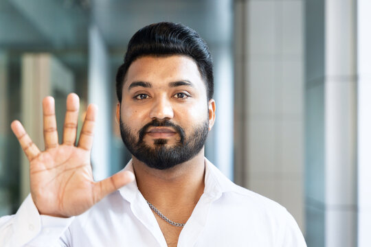 Happy smiling young south asian Indian man pointing up 5 fingers, showing number five, fifth place or 5 points gesture