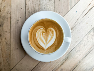 A cup of coffee latte on a wooden table. A mug of flat white coffee, latte, cappuccino on a wooden background. Coffee art. Heart flower shape latte art