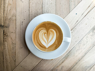A cup of coffee latte on a wooden table. A mug of flat white coffee, latte, cappuccino on a wooden background. Coffee art. Heart flower shape latte art