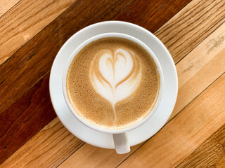 A cup of coffee latte on a wooden table. A mug of flat white coffee, latte, cappuccino on a wooden background. Coffee art. Heart flower shape latte art