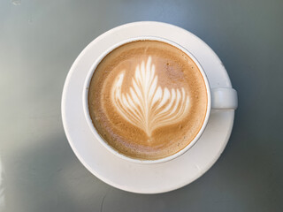 A cup of coffee latte on a grey table. A mug of flat white coffee on a grey background. Coffee art. Heart flower shape latte art. Copy space.