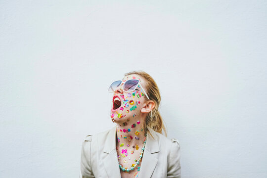 Woman with stickers on face screaming in front of white background