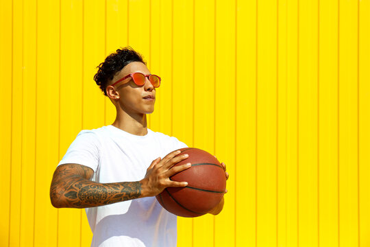 Man Holding Basketball In Front Of Yellow Wall